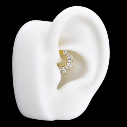 Clicker dorado con circones marquesa puesto en un piercing daith en maqueta de oreja