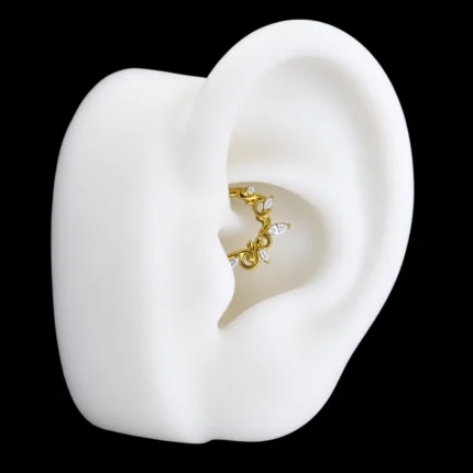 Aro clicker dorado con filigrana y circones puesto en piercing daith