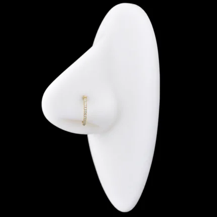 Aro clicker dorado con pavé de circones blancos puesto en el nostril de una nariz de maqueta