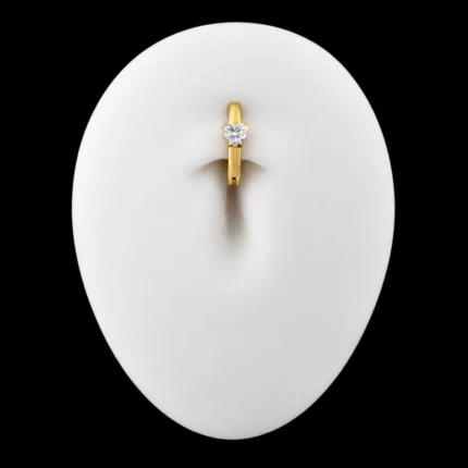 Clicker de ombligo Lateral Corazón dorado puesto en maqueta de abdomen