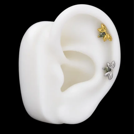 Tops flor de loto dorado y plateado puestos en el hélix de una maqueta de oreja