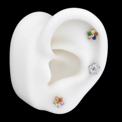 Tops flor de circones de colores y blancos puestos en hélix y lóbulo de una maqueta