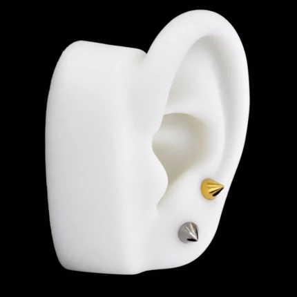 Tops de punta cónica de 5 mm dorado y plateado puestos en el lóbulo de una oreja de maqueta